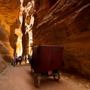 Petra, Jordan- June 10, 2014: Tourists making their way down the siq to the Treasury in Petra, Jordan. The lost city of Petra is one of the largest archaeological sites in the world.